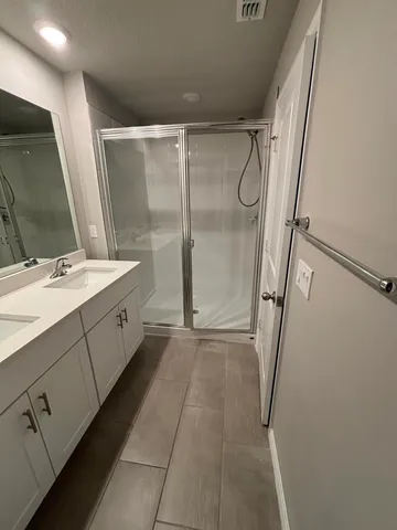 a bathroom with a double vanity sink toilet mirror and shower