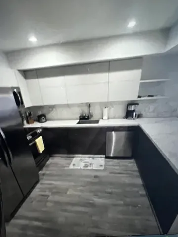 a kitchen with kitchen island stainless steel appliances a sink a counter top space and cabinets