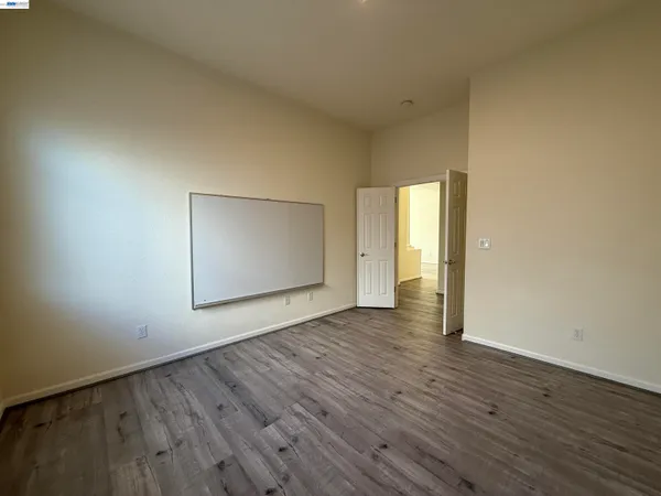 a view of an empty room with wooden floor and closet