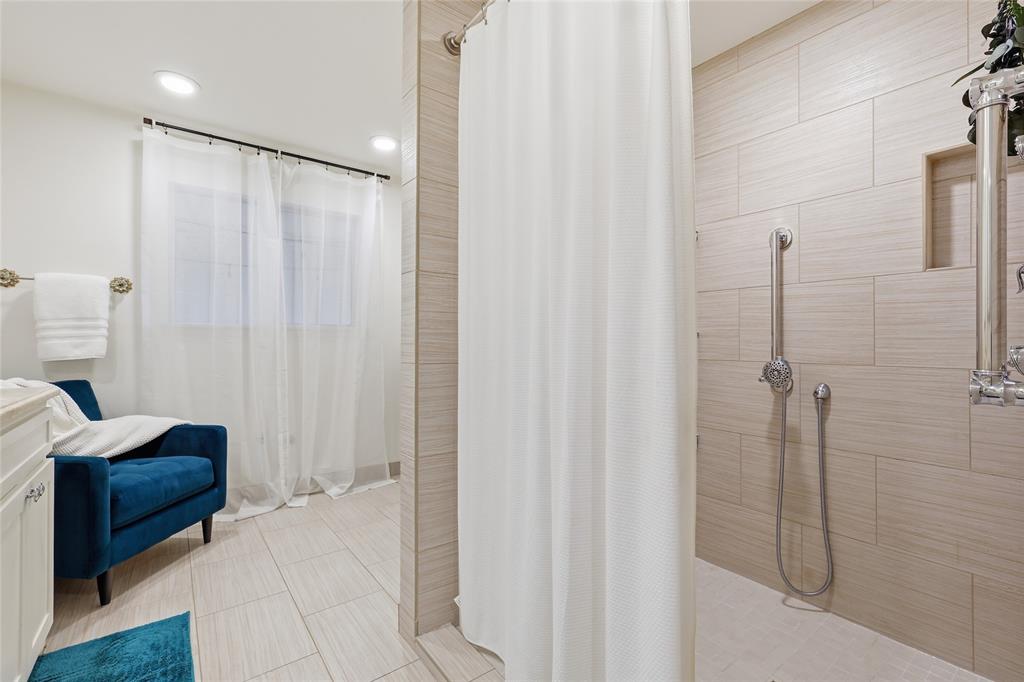 823 Ridgecrest Circle Denton, TX 76205 - Photo 22 of 40 Walk-in shower featuring light-toned large format tile, built-in shower niche, and a contrasting white shower curtain
