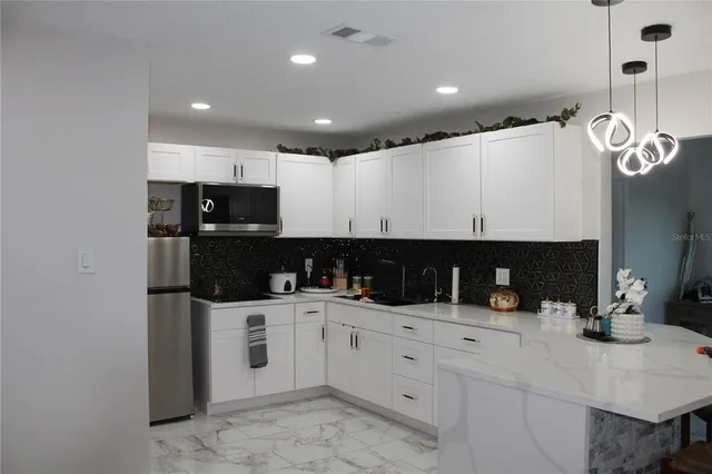 a kitchen with white cabinets and sink