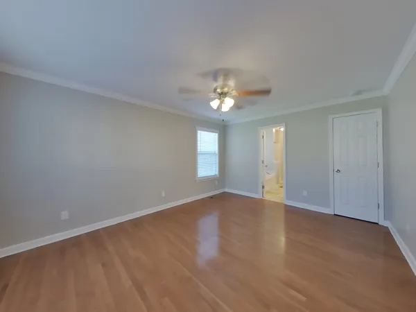 a view of an empty room with chandelier and wooden floor