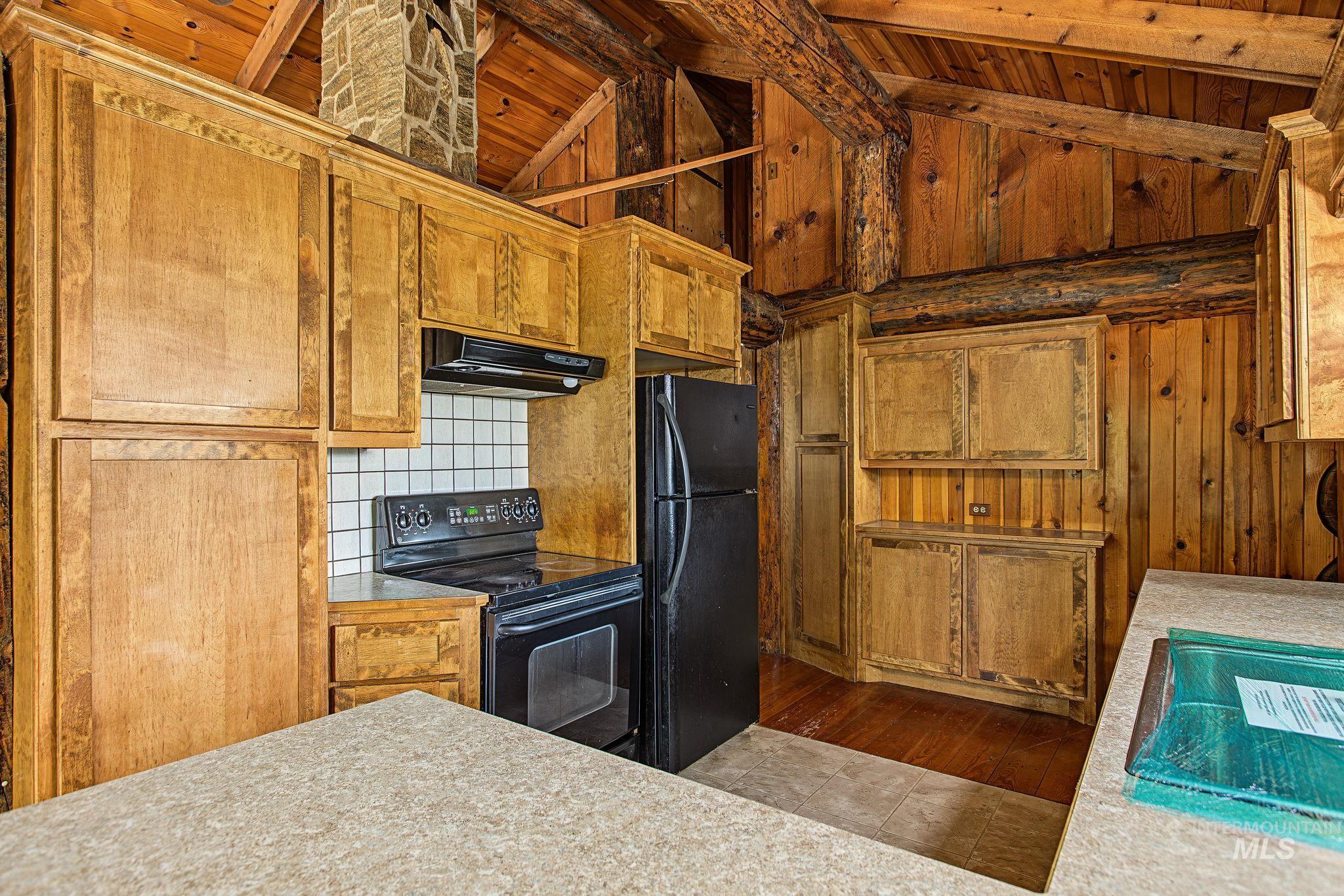 2926 Wells Bench Road Orofino, ID 83544 - Photo 13 of 48 Wood-finish cabinetry, tile backsplash, stone-clad chimney, exposed wood beams, and textured countertops