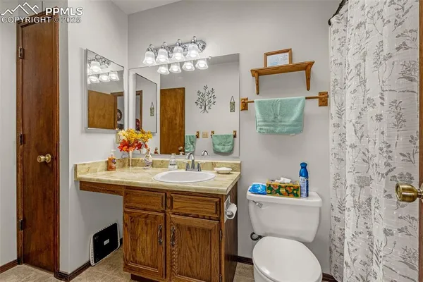 a bathroom with a granite countertop toilet sink and mirror
