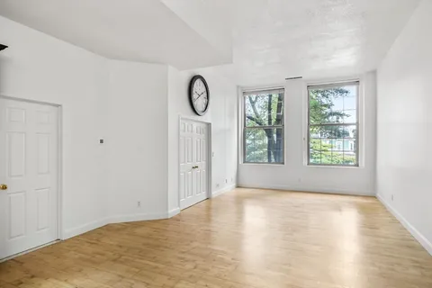 a view of an empty room with a window and wooden floor