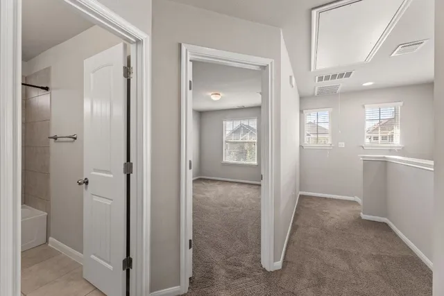 a view of a hallway with wooden floor and a bathroom