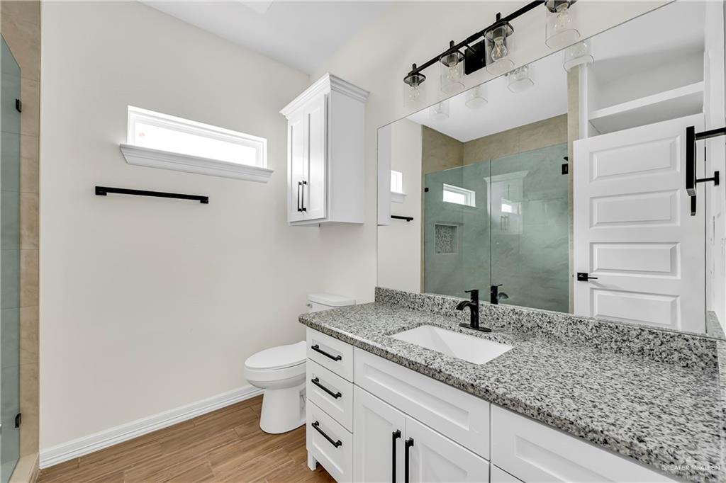 3516 East Alexa Street Edinburg, TX 78542 - Photo 13 of 25 a bathroom with a granite countertop sink a toilet and a mirror