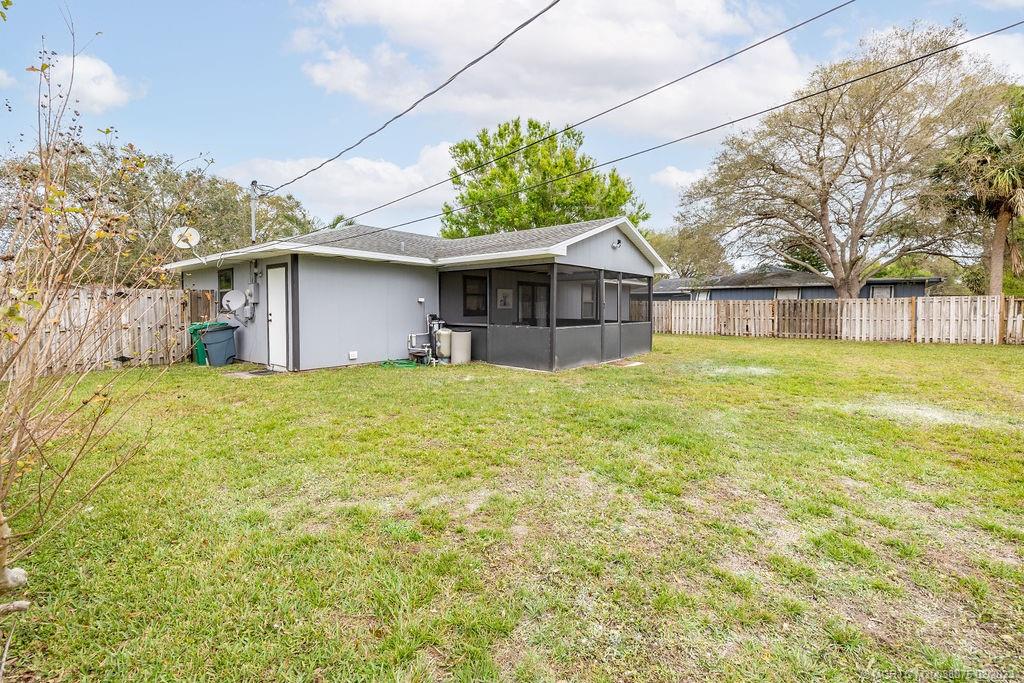 6803 Salerno Road Fort Pierce, FL 34951 - Photo 15 of 65 a white house that has a small yard and trees in the background