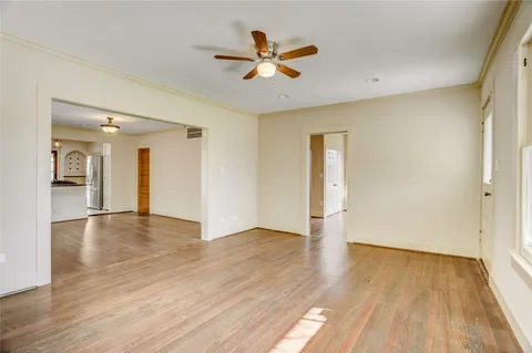 an empty room with wooden floor and a ceiling fan