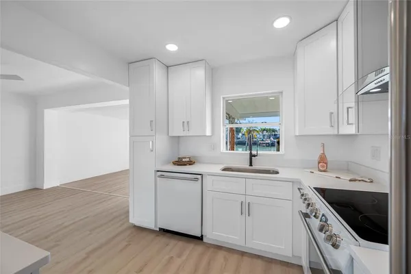 a kitchen with stainless steel appliances a white stove top oven cabinets and a wooden floor