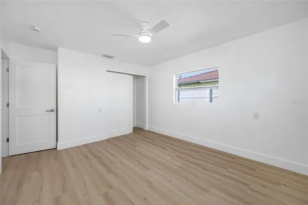an empty room with wooden floor and windows