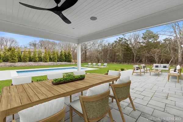 a view of a patio with a dining table and chairs with a small yard