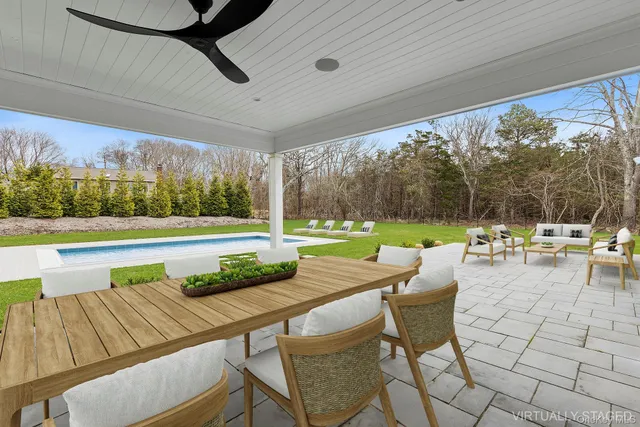 a view of a patio with a dining table and chairs with a small yard