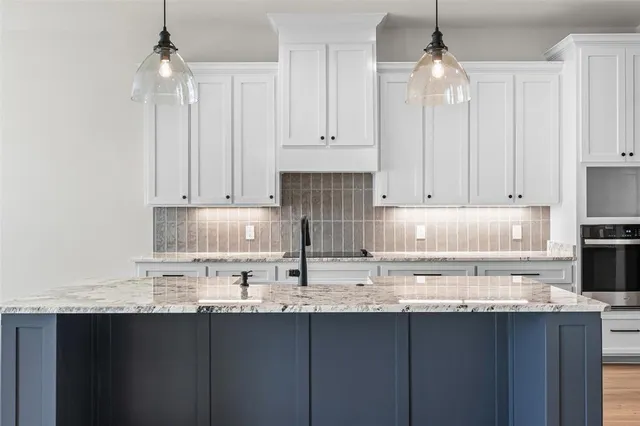 a kitchen with kitchen island granite countertop a sink cabinets and stainless steel appliances