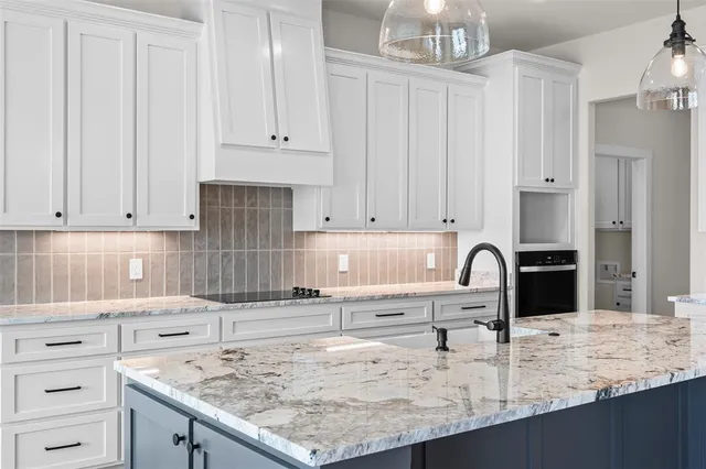 a kitchen with granite countertop a sink a stove and cabinets