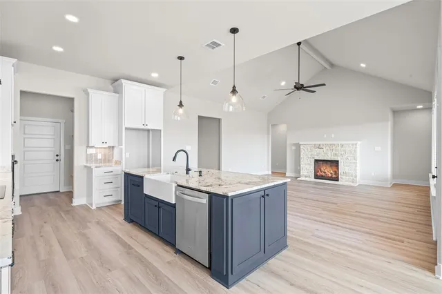 a large kitchen with stainless steel appliances granite countertop a large center island a stove a refrigerator and a fireplace