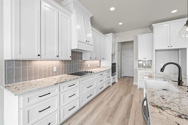 a kitchen with granite countertop white cabinets and stainless steel appliances