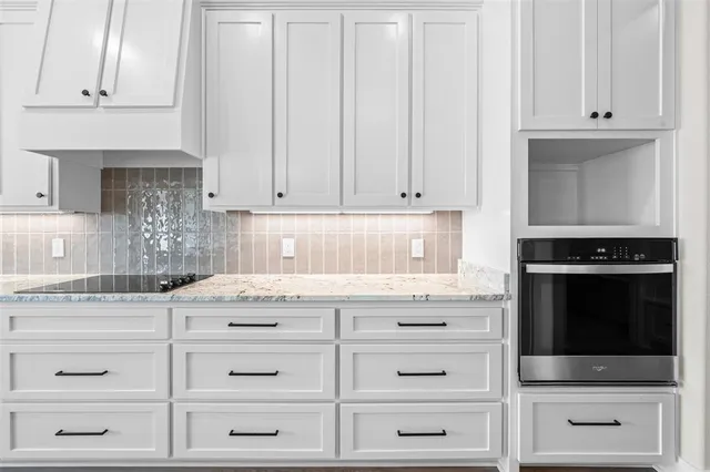 a kitchen with granite countertop white cabinets and stainless steel appliances