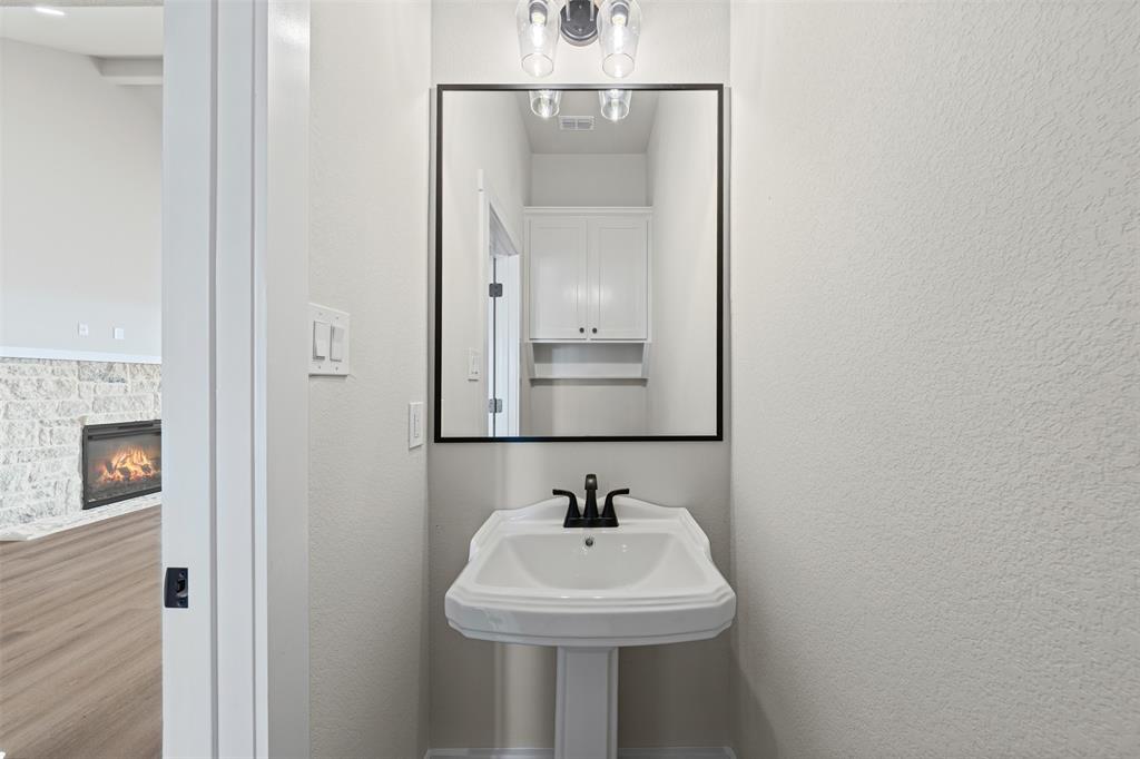 900 Day Star Drive Hewitt, TX 76643 - Photo 25 of 40 Bathroom featuring a stone fireplace, a textured wall, and wood finished floors