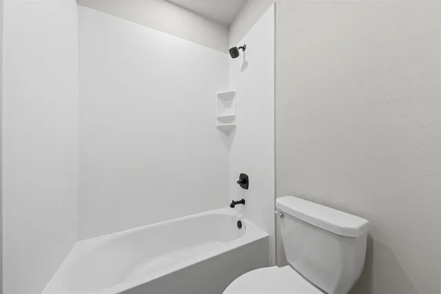 a white toilet sitting next to a bath tub