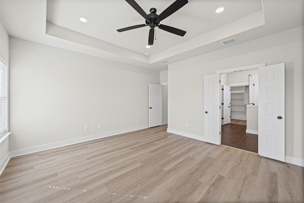 900 Day Star Drive Hewitt, TX 76643 - Photo 35 of 40 Unfurnished bedroom featuring a spacious closet, a tray ceiling, light wood-style flooring, recessed lighting, and a ceiling fan