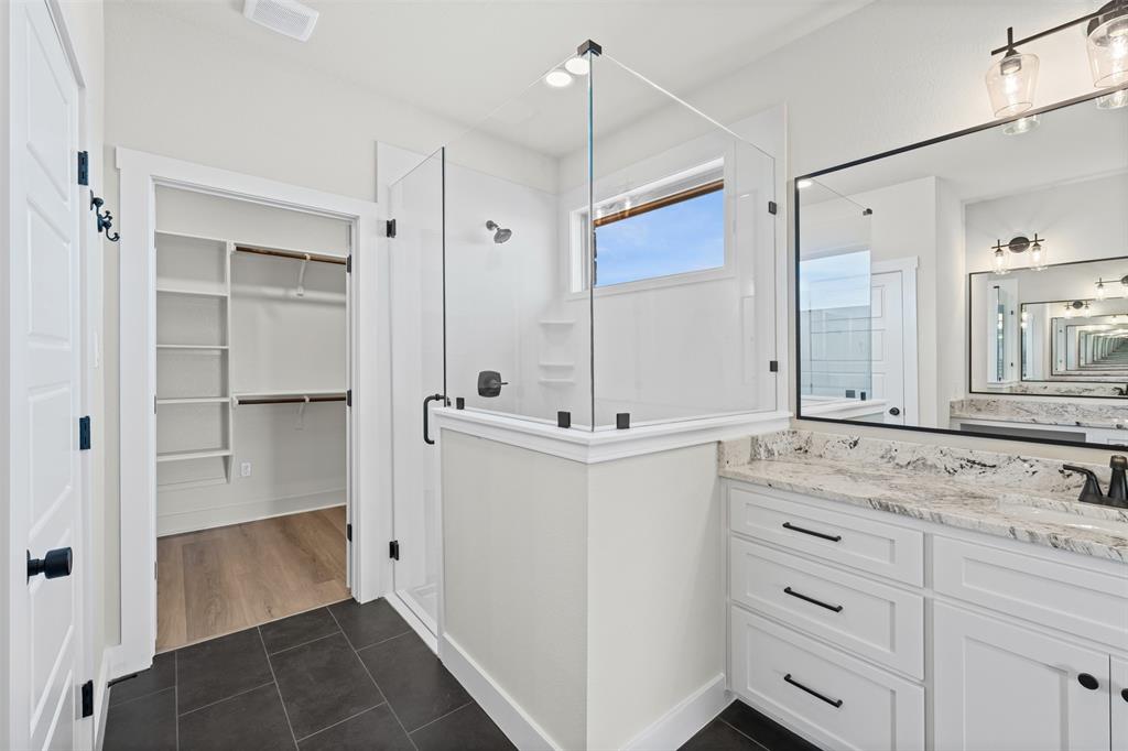 900 Day Star Drive Hewitt, TX 76643 - Photo 38 of 40 Full bath featuring dark tile patterned floors, vanity, a stall shower, and a spacious closet