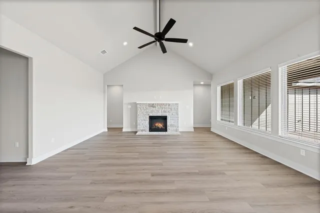a view of a livingroom with a fireplace a ceiling fan and wooden floor