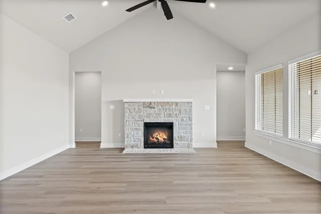 a view of an empty room with wooden floor fireplace and a window