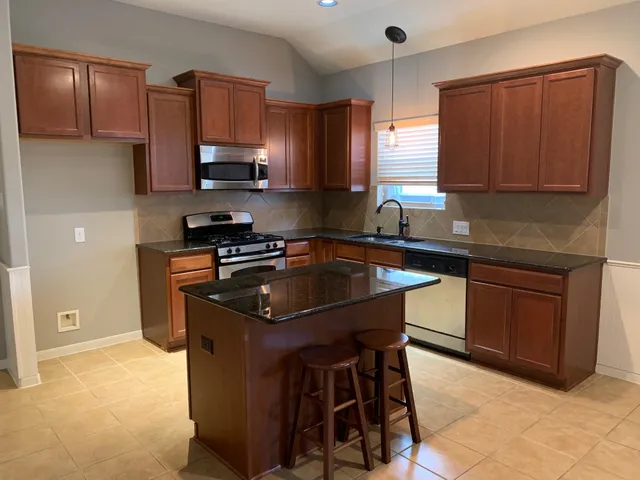 a kitchen with kitchen island granite countertop a sink counter top space appliances and cabinets