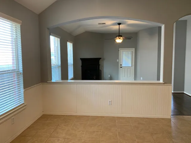 en view of an empty room with wooden floor and a window