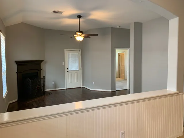 an empty room with wooden floor and hallway
