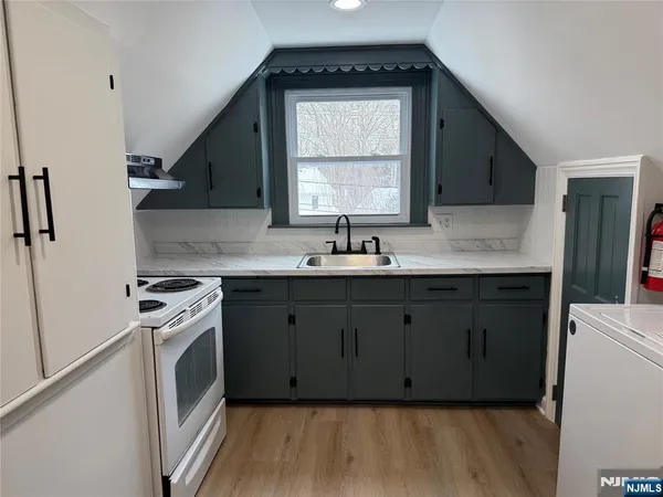 a kitchen with stainless steel appliances a sink cabinets and a wooden floor