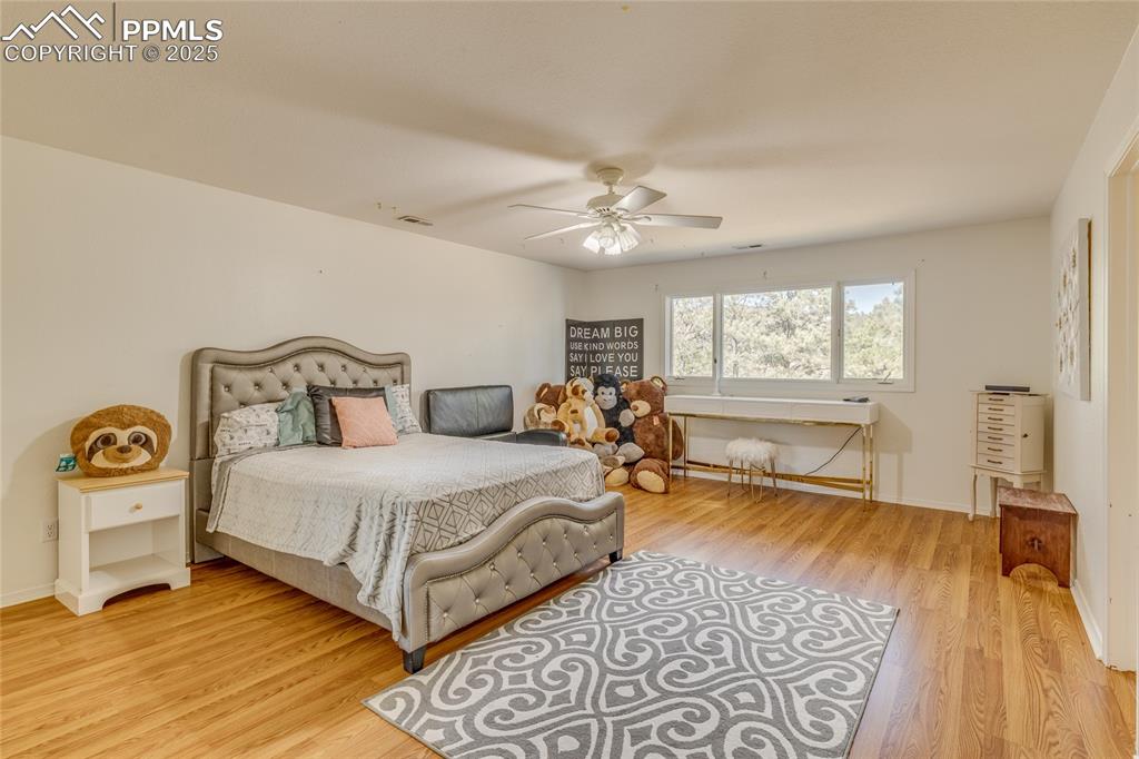 15410 South Perry Park Road Larkspur, CO 80118 - Photo 20 of 28 a spacious bedroom with a bed and wooden floor