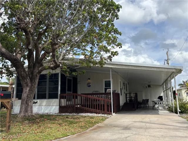a view of a house with a porch and a large tree