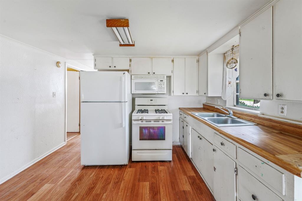 400 South Pecan Street Hamilton, TX 76531 - Photo 8 of 19 a kitchen with stainless steel appliances a refrigerator sink and white cabinets