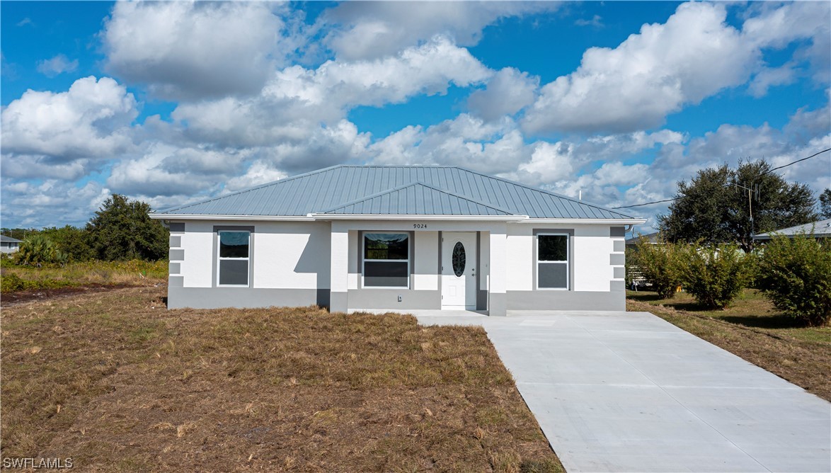 a front view of house with yard and trees in the background