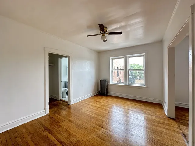 an empty room with wooden floor fan and windows