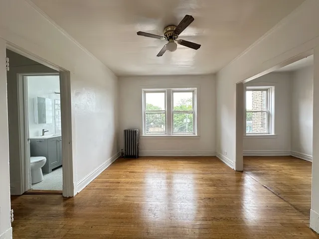 a view of empty room with wooden floor and fan