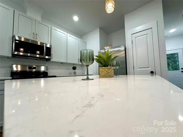 a kitchen with stainless steel appliances a stove a microwave a sink and white cabinets