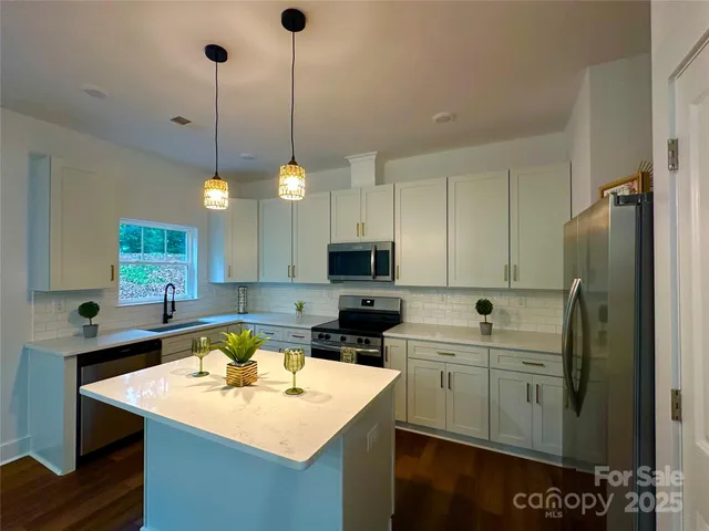 a kitchen with stainless steel appliances a stove a sink a refrigerator a center island a stove and a center island