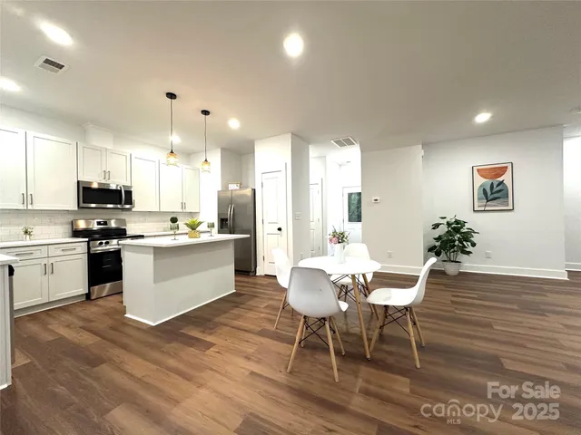 a kitchen with stainless steel appliances kitchen island granite countertop a dining table chairs and view living room