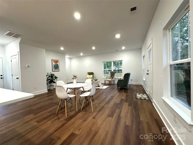 a living room with furniture a large window wooden floor and a rug