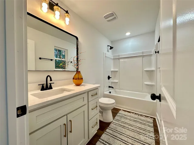 a spacious bathroom with double sink a toilet a shower and a window