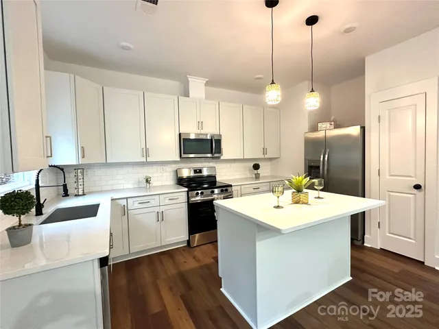 a kitchen with a sink a stove a refrigerator and white cabinets