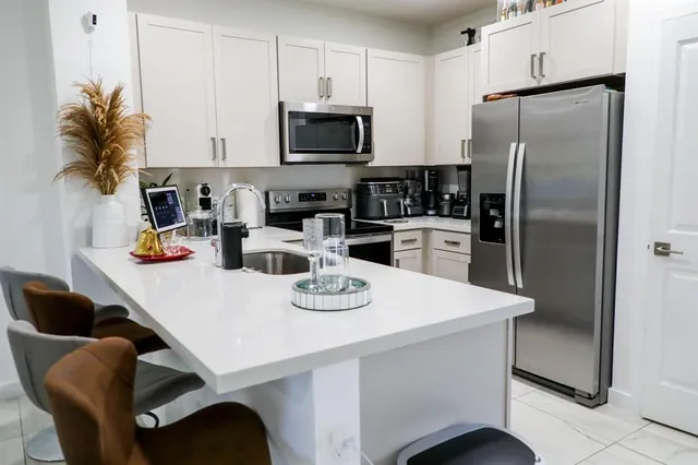 a kitchen with stainless steel appliances a table chairs and a refrigerator