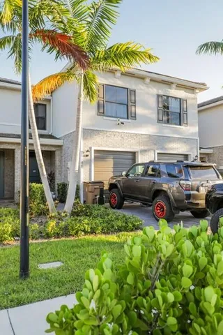 a view of a house with a cars park side of a road