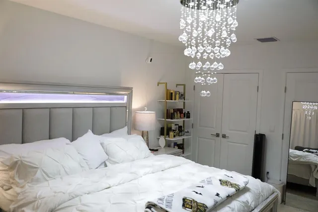 a bedroom with a large bed and a chandelier