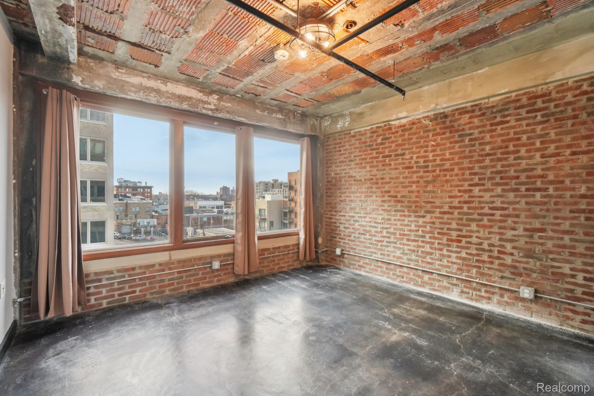 2915 John R Street Detroit, MI 48201 - Photo 16 of 30 Spare room featuring brick wall, a view of city, and unfinished concrete floors