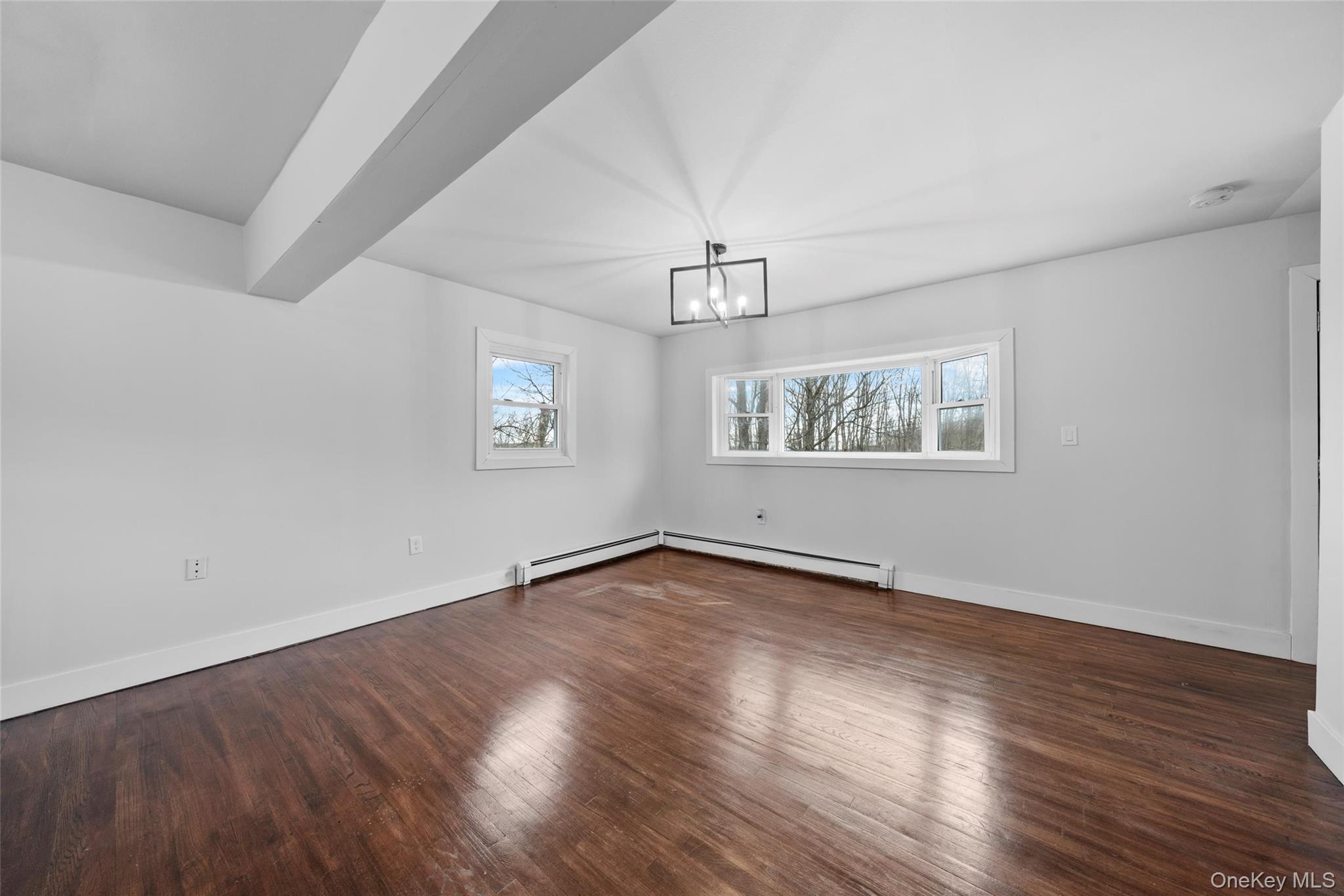 57 School Road Monroe, NY 10950 - Photo 17 of 33 an empty room with wooden floor chandelier and windows
