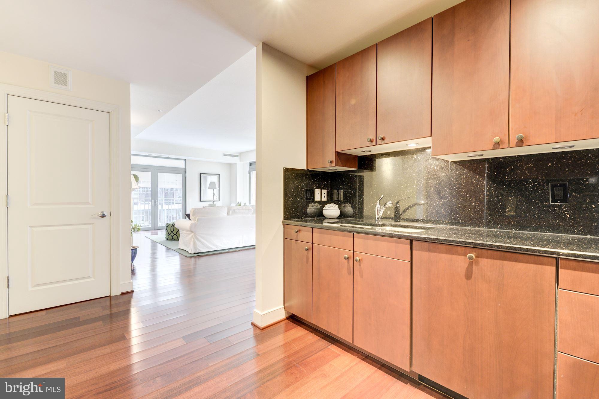 2425 L Street Northwest, Unit 539 Washington, DC 20037 - Photo 12 of 31 a kitchen with granite countertop wooden cabinets a sink and dishwasher
